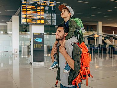 Vater mit seinem Sohn auf dem Rücken am Flughafen