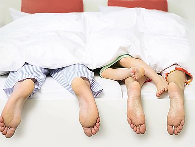 Kinder, die auf dem Bauch mit im Bett der Eltern liegen