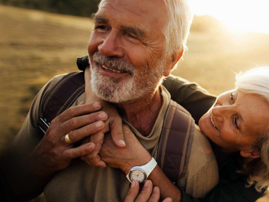 Ein älteres Paar umarmt sich auf einem Feld