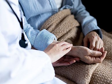 Eine Ärztin hält die Hand einer Seniorin.