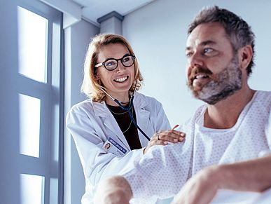 Eine Ärztin untersucht einen Patienten in einem Krankenhauszimmer.