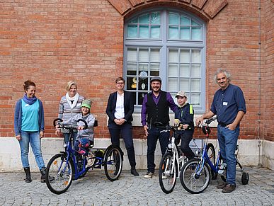 Eine Gruppe von Menschen, darunter zwei Kinder auf Therapiefahrrädern