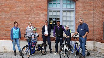 Eine Gruppe von Menschen, darunter zwei Kinder auf Therapiefahrrädern