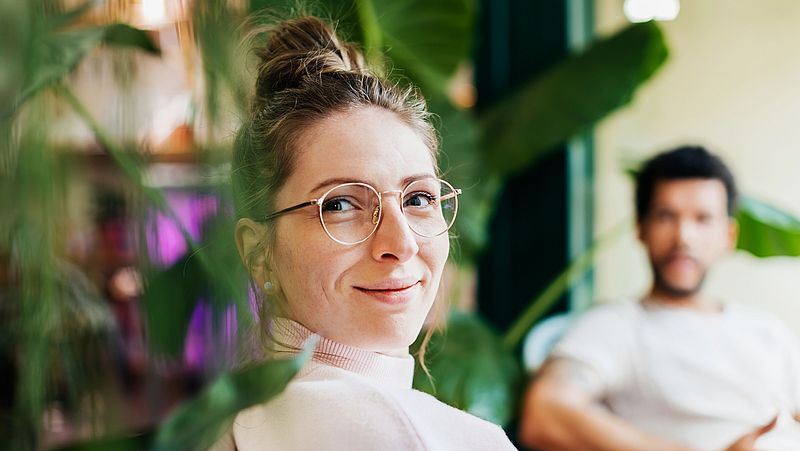 Jüngere Frau mit Brille und Dutt lächelt