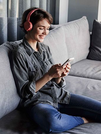 Frau sitzt auf dem Sofa und schaut auf ihr Smartphone