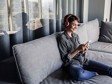 Frau sitzt auf dem Sofa und schaut auf ihr Smartphone