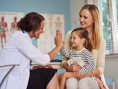 Ärztin freut sich mit einem Kind und seiner Mutter