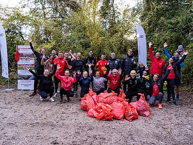 Eine Gruppe Menschen posiert mit dem gesammelten Müll einer Aufräumaktion