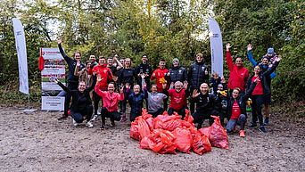 Eine Gruppe Menschen posiert mit dem gesammelten Müll einer Aufräumaktion