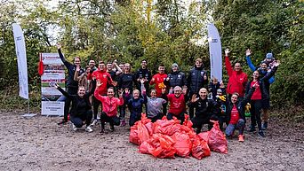 AudiBKK Oktober 2021 Ploggin Auwaldsee Eine Gruppe Menschen posiert mit dem gesammelten Müll einer Aufräumaktion