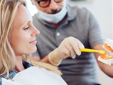 Ein Zahnarzt demonstriert richtiges Putzen an einem Modell