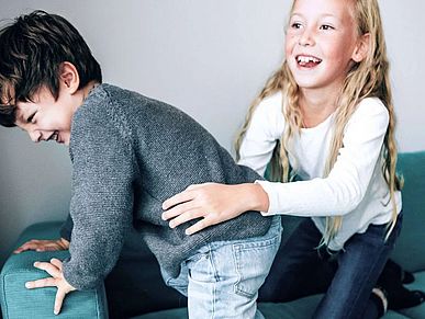 Zwei Kinder spielen auf dem Sofa