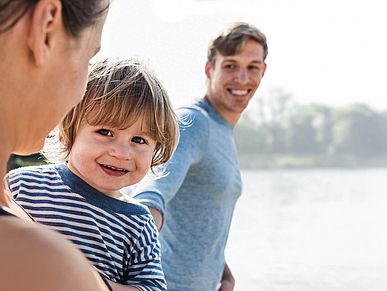 Junge Familie, die in die Kamera lacht.