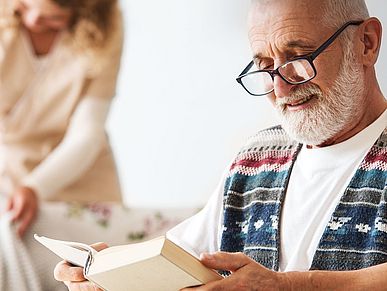 Älterer Mann liest ein Buch in einer Pflegeeinrichtung