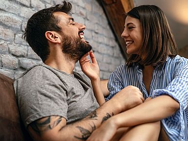 Pärchen sitzt lachend auf dem Sofa