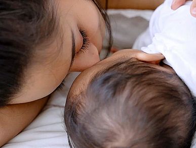 Mama kuschelt im Wochenbett mit neugeborenem Kind