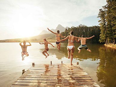 Eine Gruppe von jungen Menschen springt in einen See