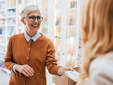 Frau kauft ein Medikament in der Apotheke.