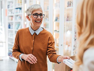 Frau kauft ein Medikament in der Apotheke.