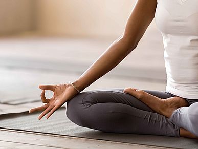 Eine Frau sitzt in einer Yoga Pose auf einer Matte