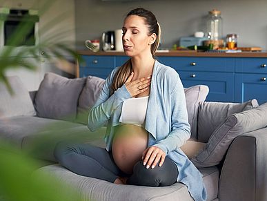 Schwangere Frau sitzt auf dem Sofa