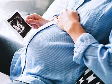 Schwangere Frau schaut sich Ultraschallbild an