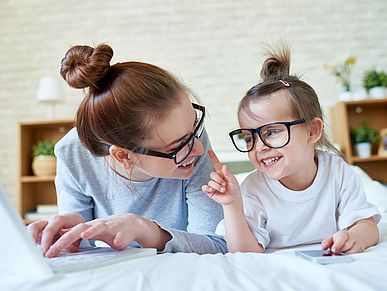 Mutter und Kind tragen eine Brille und lachen