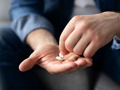 Ein Mann hält Tabletten in seinen Händen.