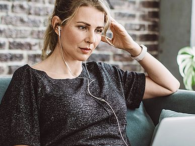 Frau sitzt auf dem Sofa vor ihrem Laptop