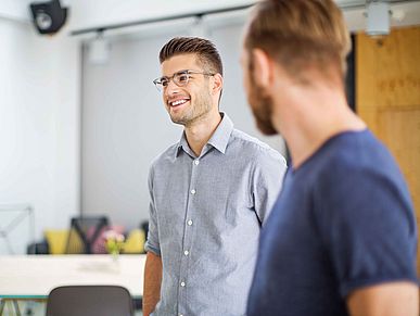 Lächelnde junge Unternehmer im Gespräch mit Kollegen im Büro